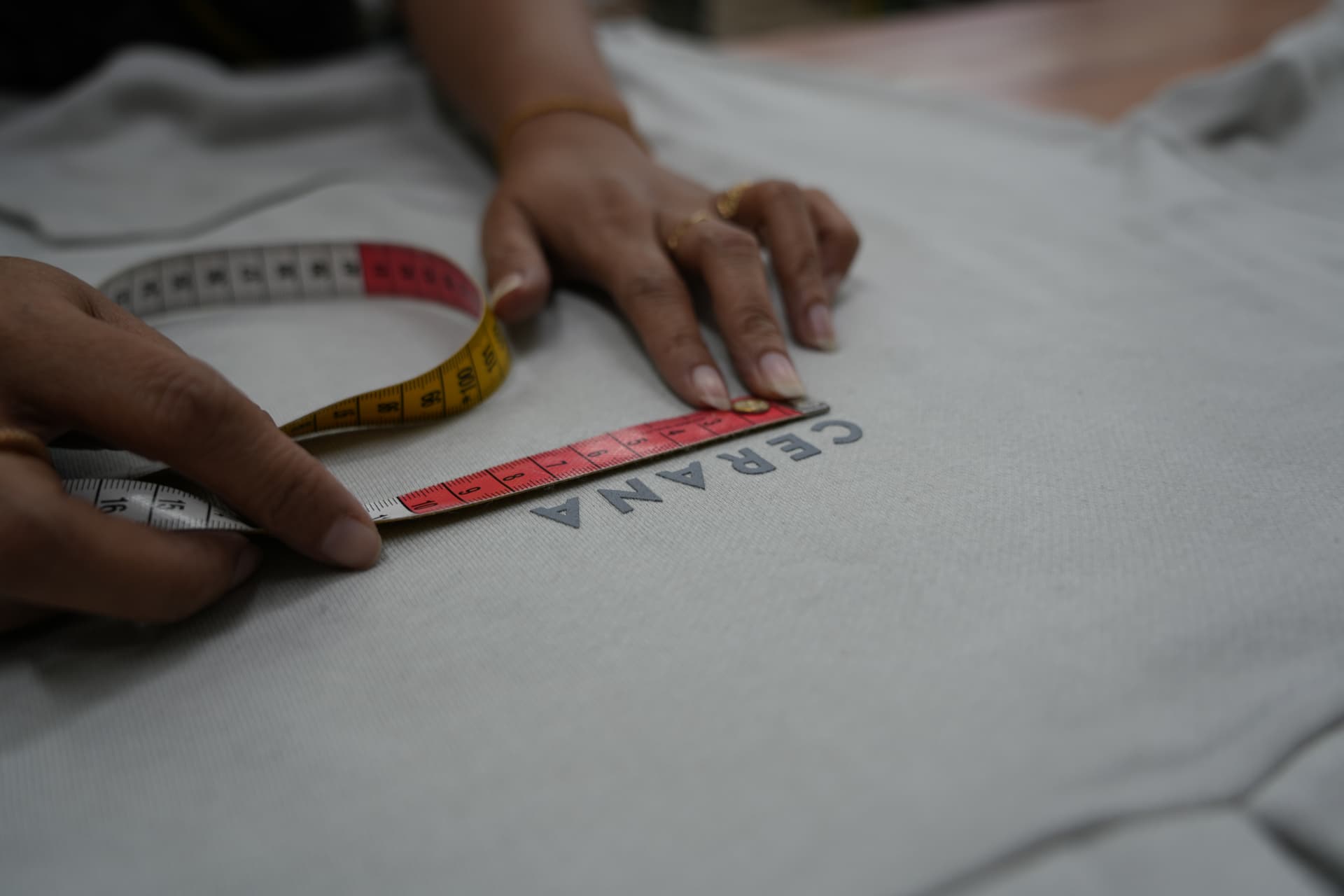 A tape measure laid across the chest print of a Cerana tee in the factory in Bali